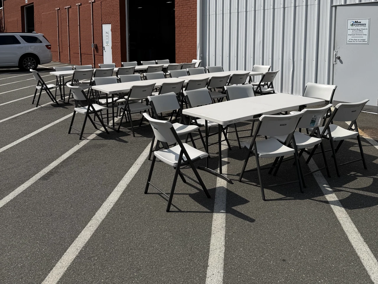 Rental tables and white folding chairs set up outside a commercial building