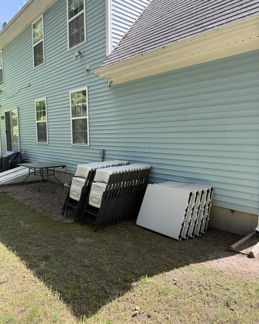 Folded chairs and tables dropped off beside a house, ready for the party
