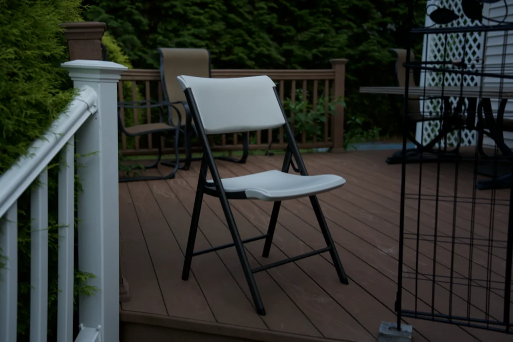 White folding chair on a wooden deck in evening light