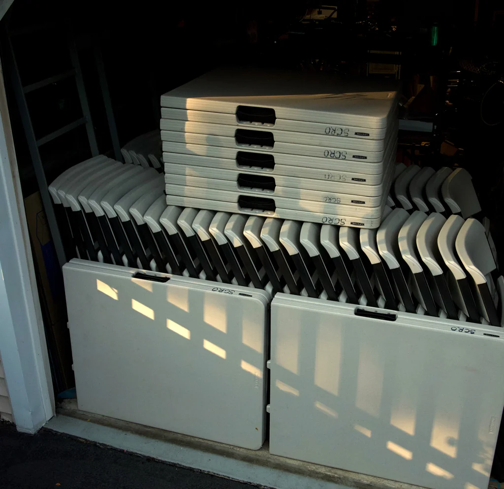 The AirPool Events rental fleet — stacked folding tables and rows of folding chairs staged for delivery